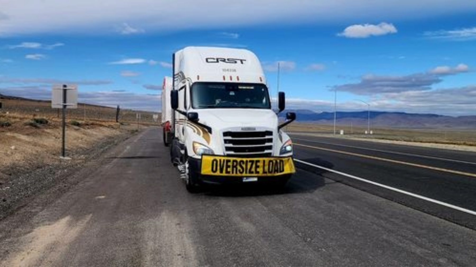 CRST truck hauling an oversized load on a highway, demonstrating owner-operator fuel efficiency strategies for long-haul trucking.